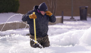 City of Richardson worker Kaleb Love stands in a frozen fountain as he takes a break from clearing ice Tuesday, Feb. 16, 2021, in Richardson, Texas. Temperatures dropped into the single digits as snow shut down air travel and grocery stores. (AP Photo/LM Otero)