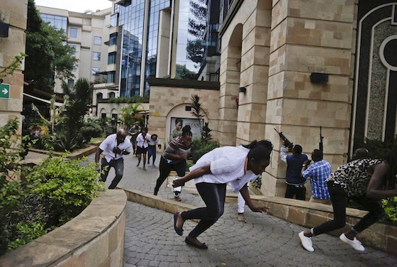 Civilians flee as security forces aim their weapons at the buildings of a hotel complex in Nairobi, Kenya, on Tuesday. Extremists launched a deadly attack on a luxury hotel in Kenya's capital, sending people fleeing in panic as explosions and heavy gunfire reverberated through the complex. A police officer said he saw bodies, "but there was no time to count the dead." (AP Photo/Khalil Senosi)