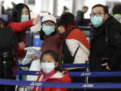 Passengers wearing masks wait in a line to check-in to a flight, Monday, Jan. 27, 2020. (AP Photo/Petr David Josek)
