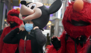 A woman wears a mask under her costume as she works in Times Square, New York, Tuesday, March 10. New York state is shuttering schools and houses of worship for two weeks in part of a suburb and sending the National Guard there to help respond to what appears to be the nation's biggest cluster of cases of the coronavirus.(AP Photo/Seth Wenig)