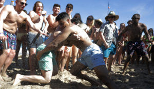 Two men wrestle each other as spring break revelers look on during a contest on the beach, Tuesday, March 17, in Pompano Beach, Florida. Many Florida beaches are turning away spring break crowds urging them to engage in social distancing. (AP Photo/Julio Cortez)