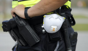 A North Charleston, South Carolina, police officer carries a protective mask around his gun belt while working traffic on March 16. The coronavirus has the potential to profoundly change law enforcement in the U.S.  as police departments are shifting resources and changing how they police while the virus strikes. (AP Photo/Mic Smith, File)