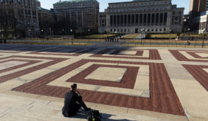 A man sits on the Columbia University campus in March in New York. (AP Photo/Mark Lennihan)