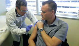 Pharmacist Michael Witte, left, gives Neal Browning, right, a shot in the first-stage safety study clinical trial of a potential vaccine for the COVID-19 coronavirus, Monday, March 16, 2020, at the Kaiser Permanente Washington Health Research Institute in Seattle. Browning is the second patient to receive the shot in the study. (AP Photo/Ted S. Warren)