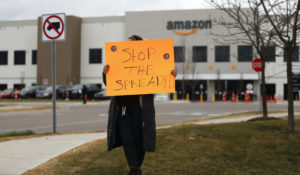 A family member of an employee holds a sign outside an Amazon fulfillment center in Michigan, April 1. Employees and family members are protesting in response to what they say is the company's failure to protect the health of its employees amid the new coronavirus COVID-19 outbreak. (AP Photo/Paul Sancya)