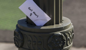 A paper envelope written with the words "Rent Money $" is left tucked in a lighting pole in the Boyle Heights east district of the city of Los Angeles on Wednesday, April 1, 2020. It's the beginning of the month, and rent is due for millions of Americans. (AP Photo/Damian Dovarganes)