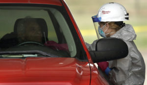 Kansas National Guard member Jessica Pal tests a man at a drive-thru COVID-19 testing site  Wednesday, May 20, 2020 in Dodge City, Kansas. (AP Photo/Charlie Riedel)