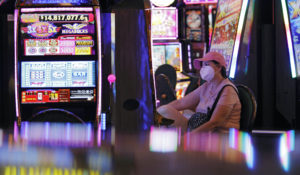A woman plays an electronic slot machine at the reopening of the Bellagio hotel and casino Thursday, June 4, 2020, in Las Vegas. Casinos in Nevada were allowed to reopen on Thursday for the first time after temporary closures as a precaution against the coronavirus. (AP Photo/John Locher)