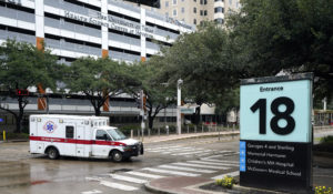 An ambulance drives through the Texas Medical Center Thursday, June 25, 2020, in Houston. The leaders of several Houston hospitals said they were opening new beds to accommodate an expected influx of patients with COVID-19, as coronavirus cases surge in the city and across the South. (AP Photo/David J. Phillip)