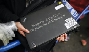A student receives her school laptop for home study at the Lower East Side Preparatory School as COVID-19 restrictions shuttered classrooms throughout the city in March. (AP Photo/John Minchillo)