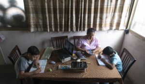 A woman helps her children with online homework at their home. Some parents are looking into teaching "pods" or "microschools" that would employ professional teachers to educate small groups of students. (AP Photo/Ariana Cubillos)
