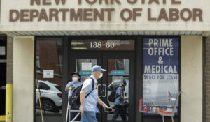 Pedestrians pass an office location for the New York State Department of Labor in Queens. (AP Photo/Frank Franklin II)