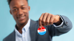 young man holding I Voted sticker