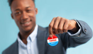 young man holding I Voted sticker