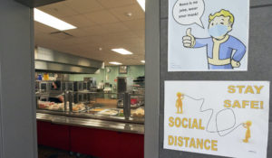 Signs remind students to social distance at the entrance to the cafeteria line, during a media tour of the Norris Middle School in Omaha, Nebraska, to show how school authorities are preparing for the return of students to school in the time of COVID-19. (AP Photo/Nati Harnik)