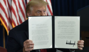 President Donald Trump signs an executive order during a news conference at the Trump National Golf Club in Bedminster, N.J., Saturday, Aug. 8, 2020. (AP Photo/Susan Walsh)