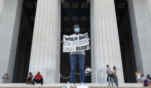 Yinka Onayemi holds a sign as he stands quietly on the steps of the Lincoln Memorial looking out over the National Mall in Washington, Sunday, May 31, 2020, to protest the death of George Floyd. (AP Photo/Carolyn Kaster)