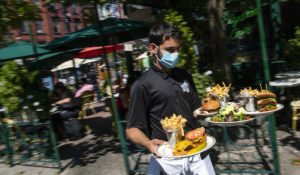 A waiter in a face mask delivers food to the tables outside of a local restaurant during  in Hoboken, New Jersey. (AP Photo/Eduardo Munoz Alvarez)