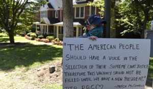 A protester stands outside the house of Senate Majority Leader Mitch McConnell, R-Ky., in Louisville, Kentucky, on Saturday. (AP Photo/Timothy D. Easley)