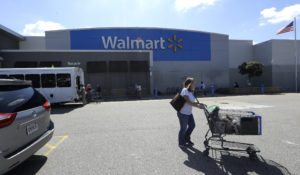 A customer pushes a shopping cart Tuesday, Sept. 3, 2019, outside a Walmart store, in Walpole, Mass. (AP Photo/Steven Senne)
