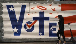 A woman walks past a voting sign painted on a wall in  Los Angeles. (AP Photo/Jae C. Hong)