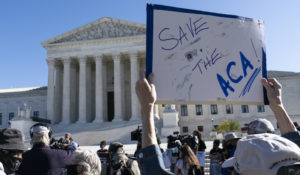 A demonstrator holds a sign in front of the U.S. Supreme Court as arguments are heard about the Affordable Care Act, Tuesday, Nov. 10, 2020, in Washington. (AP Photo/Alex Brandon)