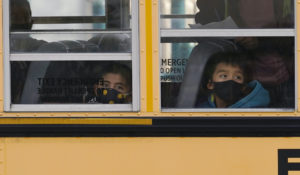 In-person elementary school students board on school bus after school in Wheeling, Ill., Thursday, Nov. 19, 2020. (AP Photo/Nam Y. Huh)