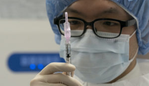 A pharmacist poses with a syringe in a clean room where doses of COVID-19 vaccines will be loaded into syringes, Wednesday, Dec. 9, 2020 at Mount Sinai Queens hospital in New York. (AP Photo/Mark Lennihan)
