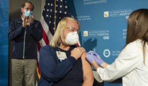 Health and Human Services Secretary Alex Azar, left, applauds as nurse Lillian Wirpsza administers a COVID-19 vaccine to emergency department nurse Barbara Neiswander, center, at George Washington University. (AP Photo/Jacquelyn Martin, Pool)