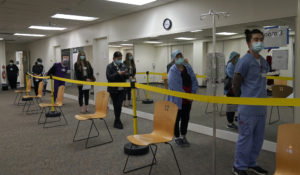 Health care workers wait in line to receive the Pfizer-BioNTech COVID-19 vaccine at Seton Medical Center in Daly City, Calif., Thursday, Dec. 24, 2020. (AP Photo/Jeff Chiu)