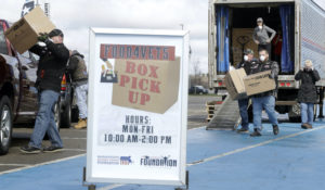 Volunteers distribute boxes of food to veterans and their families in a parking lot at Gillette Stadium, in Foxborough, Mass., Tuesday, March 31, 2020. (AP Photo/Steven Senne)
