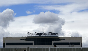 The Los Angeles Times building is seen behind a fence behind the Los Angeles International Airport, Friday, April 10, 2020. (AP Photo/Richard Vogel)