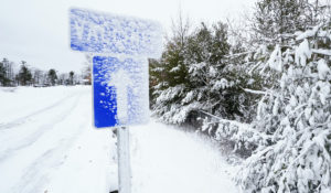 A snow covered sign directs drivers to a COVID-19 vaccine site, which was closed due to winter weather, at a park and ride lot, Tuesday, Feb. 2, 2021, in Londonderry, N.H. Vaccines at the site were cancelled on Tuesday, after a storm dumped about a foot in some areas of the state. (AP Photo/Charles Krupa)