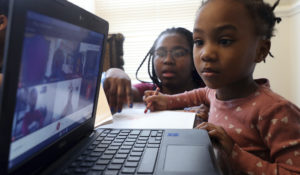 4-year-old Lear Preston of Scott Joplin Elementary School attends her online classes as her mother Brittany Preston assists her from the side in their residence in Chicago on Wednesday, Feb. 10, 2021. Starting Thursday, Lear will return to class as the nation’s third-largest school district slowly reopens its doors following a bitter fight with the teachers union over COVID-19 safety protocols. (AP Photo/Shafkat Anowar)