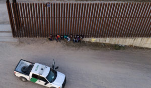 A U.S. Customs and Border Protection vehicle is seen next to migrants after they were detained and taken into custody, Sunday, March 21, 2021, in Abram-Perezville, Texas. (AP Photo/Julio Cortez)