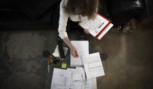 Bonney Ginett sifts through paperwork for her application to a federally-funded program to help pay back rent Thursday, March 18, 2021, in Queens. Ginett, whose massage therapy business dried up during the pandemic, applied for help in July and said she was denied in October because she failed to prove loss of income. The 65-year-old New York City resident now owes more than $26,000 in back rent on her one-bedroom apartment and fears eviction. (AP Photo/Robert Bumsted)