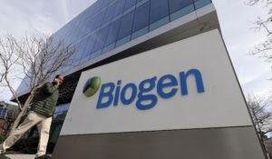 A man walks past the Biogen Inc., headquarters, Wednesday, March 11, 2020, in Cambridge, Mass. (AP Photo/Steven Senne)