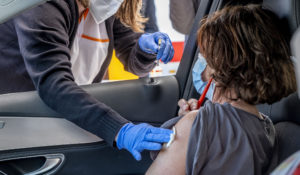 A woman sits in a car as she is vaccinated with AstraZeneca in a tent on the parking lot of a supermarket in Pforzheim, southern Germany, Wednesday, May 5, 2021. (AP Photo/Michael Probst)