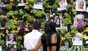 People stand near a makeshift memorial outside St. Joseph Catholic Church near the Champlain Towers South residential condo, Tuesday, June 29, 2021, in Surfside, Fla. Many people were still unaccounted for after Thursday's fatal collapse. (AP Photo/Gerald Herbert)
