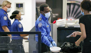 TSA officers wear protective masks at a security screening area at Seattle-Tacoma International Airport Monday, May 18, 2020, in SeaTac, Wash. (AP Photo/Elaine Thompson)