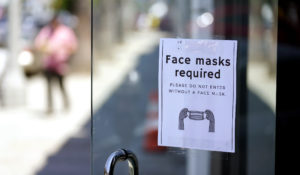 A sign advises shoppers to wear masks outside of a story Monday, July 19, 2021, in the Fairfax district of Los Angeles. (AP Photo/Marcio Jose Sanchez)