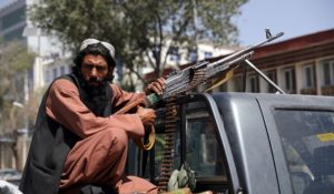 A Taliban fighter sits on the back of a vehicle with a machine gun in front of the main gate leading to the Afghan presidential palace, in Kabul, Afghanistan, on Monday. (AP Photo/Rahmat Gul)