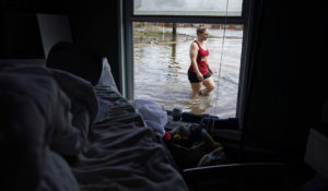 Emily Francois walks through floodwaters beside her flood damaged home in the aftermath of Hurricane Ida, Wednesday, Sept. 1, 2021, in Jean Lafitte, La. Louisiana residents still reeling from flooding and damage caused by Hurricane Ida scrambled Wednesday for food, gas, water and relief from the sweltering heat as thousands of line workers toiled to restore electricity and officials vowed to set up more sites where people could get free meals and cool off. (AP Photo/John Locher)