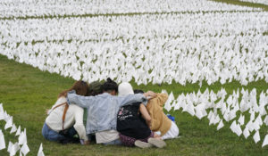 Visitors sit among white flags that are part of artist Suzanne Brennan Firstenberg's "In America: Remember," a temporary art installation to commemorate Americans who have died of COVID-19, on the National Mall in Washington, Tuesday, Sept. 21, 2021. (AP Photo/Patrick Semansky)