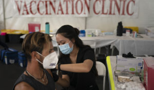 Registered nurse Noleen Nobleza, center, inoculates Julio Quinones with the COVID-19 vaccine at a clinic set up in the parking lot of CalOptima Saturday, Aug. 28, 2021, in Orange, Calif. (AP Photo/Jae C. Hong)