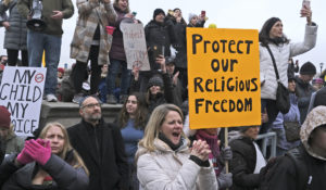People hold signs during a protest at the state house in Trenton, N.J., Monday, Jan. 13, 2020. (AP Photo/Seth Wenig)