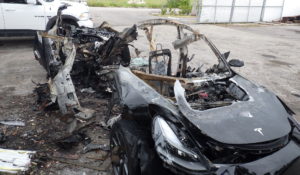 This image provided by the National Transportation Safety Board shows damage to a 2021 Tesla Model 3 following a crash in September, 2021, in Coral Gables, Fla. The Tesla driver who died with a passenger in a fiery September crash near Miami accelerated to 90 mph in the seconds before he lost control and smashed into trees, federal investigators said. (NTSB via AP)
