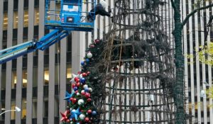 A worker disassembles a Christmas tree outside Fox News headquarters in New York on Wednesday after it was destroyed by fire. (AP Photo/Richard Drew)