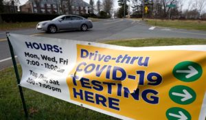 A motorist steers their car past a sign that calls attention to COVID-19 testing on Wednesday in Brockton, Mass. (AP Photo/Steven Senne)