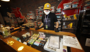 In this Wednesday, April 8, 2020, photograph, Ben Prater checks over his stock at his marijuana dispensary  in Denver during a statewide stay-at-home order. (AP Photo/David Zalubowski)